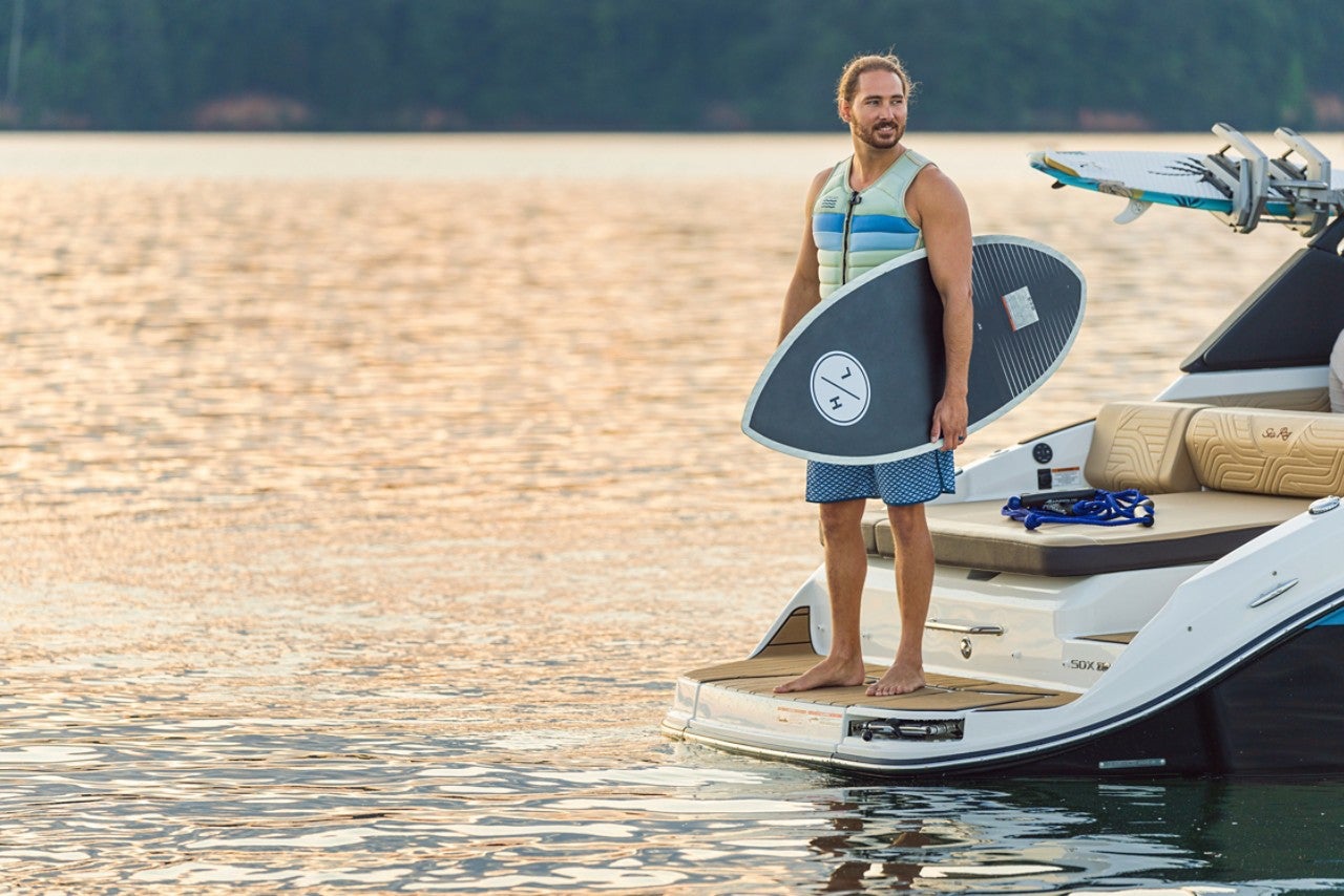 Man with wakesurf board on an SDX 250 Surf at sunset