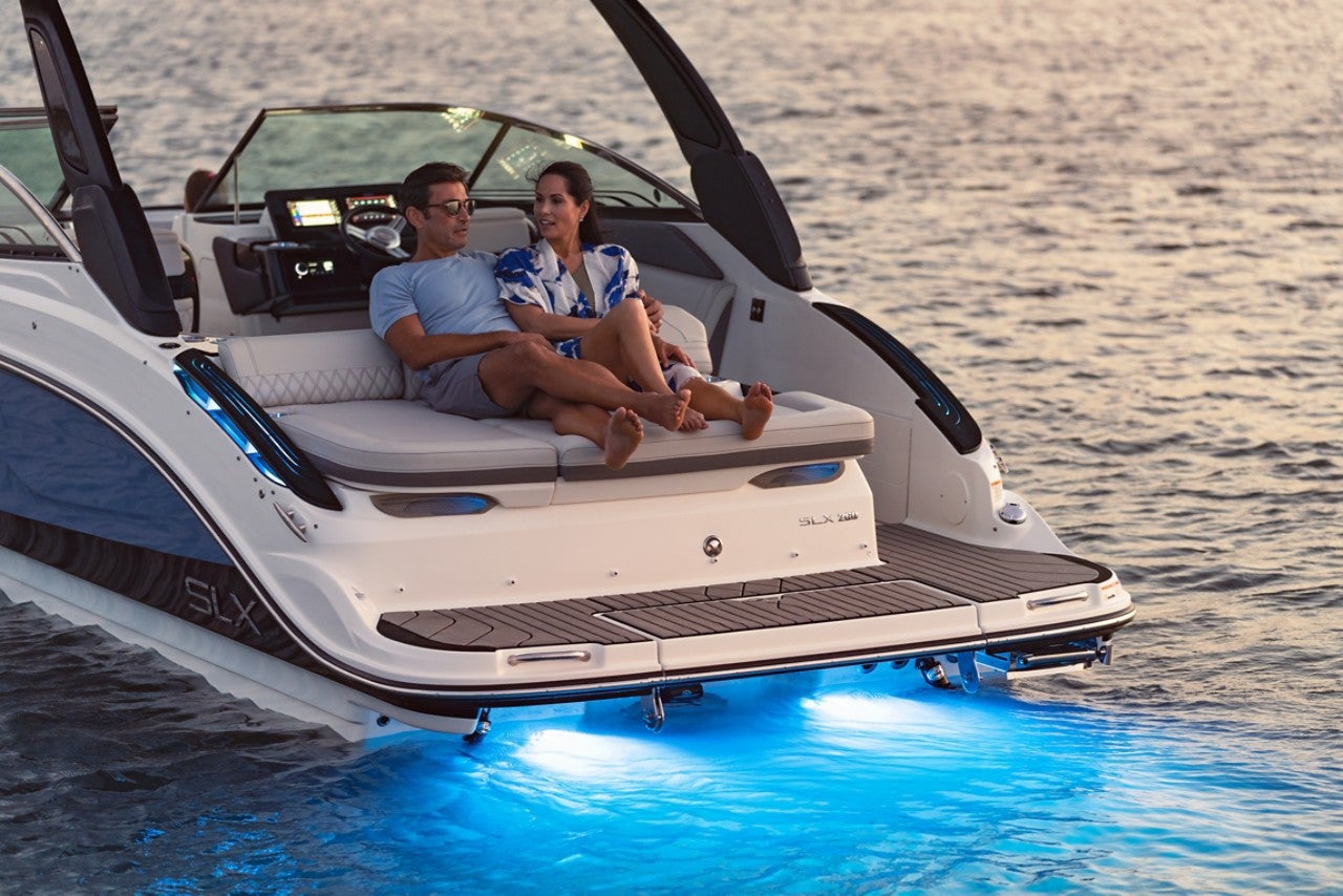 Couple lounging on the sunpad of an SLX 260 at twilight