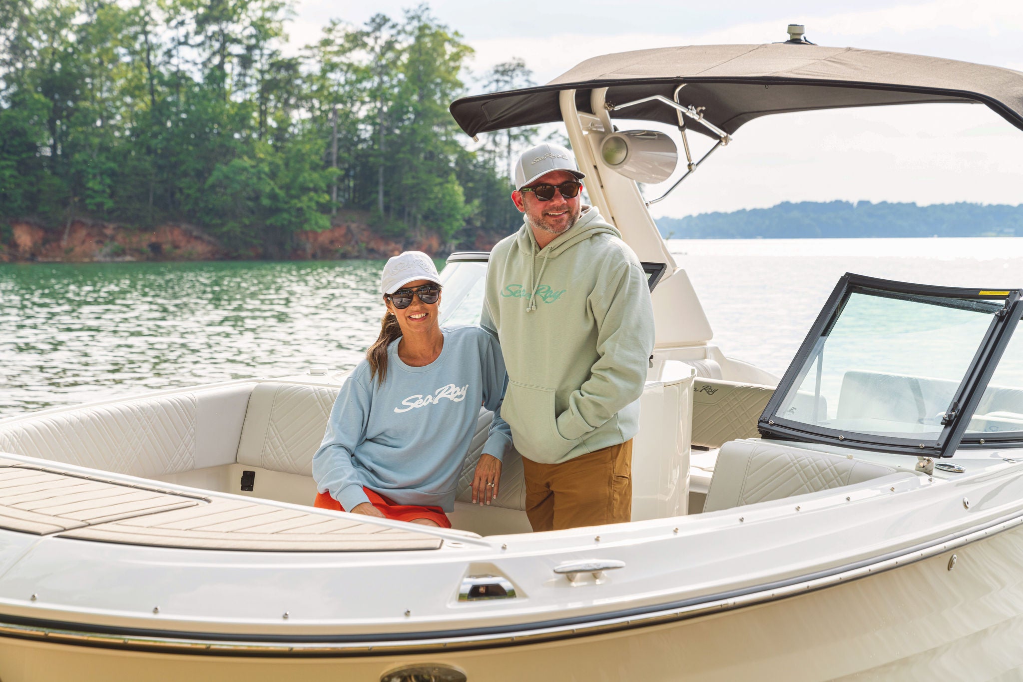 Man wearing a hoodie and woman wearing a crew neck on a Sea Ray boat