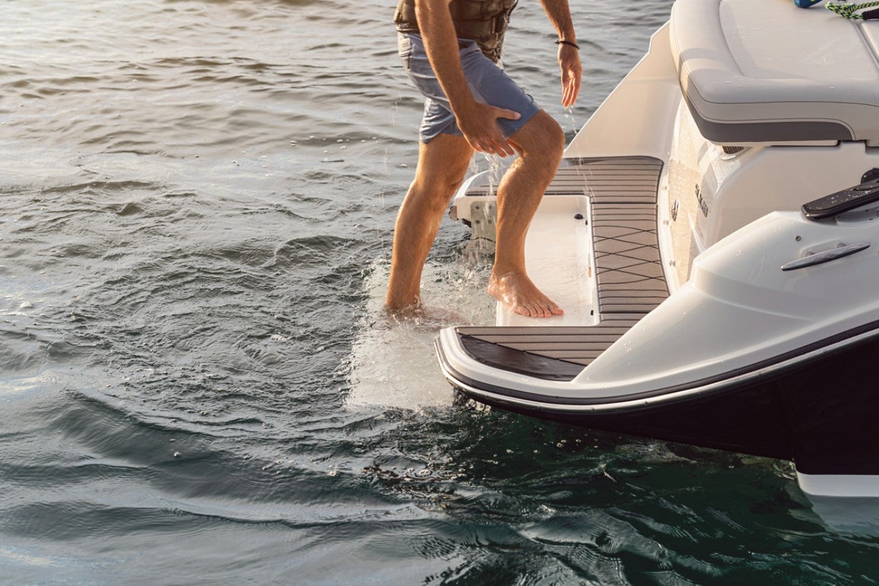 Man using the swim step to board an SLX 260 Surf