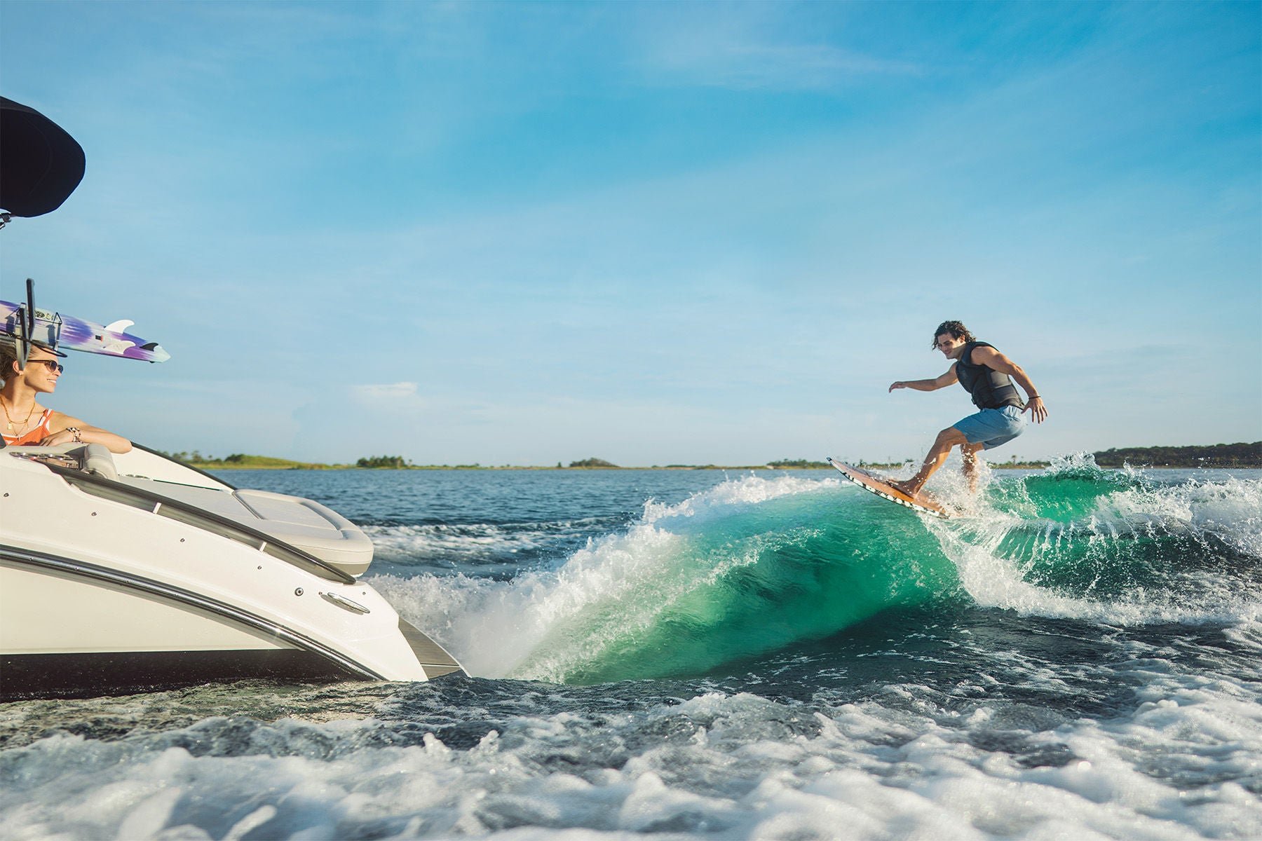 Couple wakeboarding on a Sea Ray SLX 260 Surf stern view